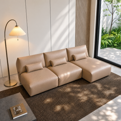 Beige three-seat modular sofa with lumbar cushions in a sunlit modern room.