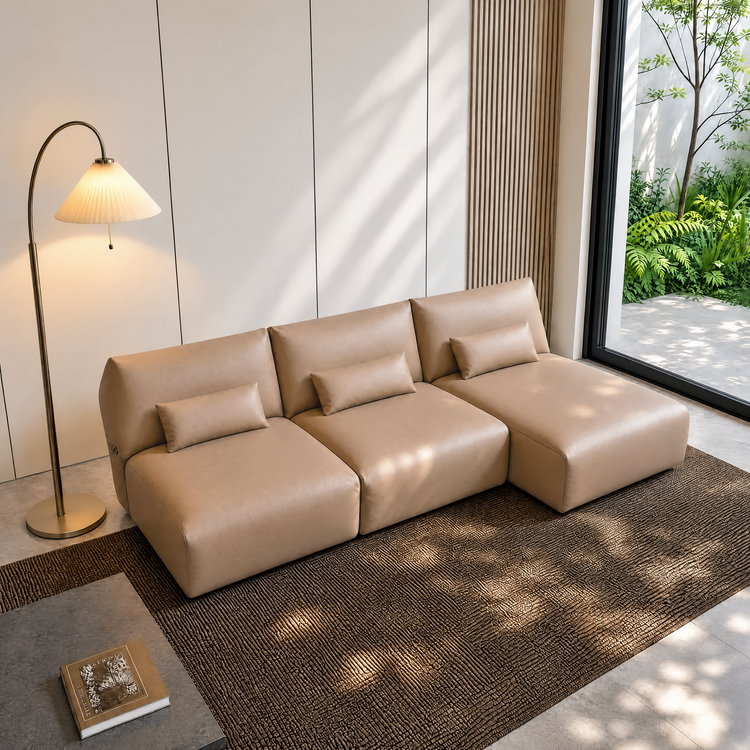 Beige three-seat modular sofa with lumbar cushions in a sunlit modern room.