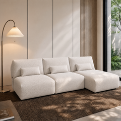 White three-seat modular sofa with a chaise and three lumbar pillows.