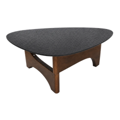 Low triangular table has rounded corners and a dark textured top, Three warm brown curved supports form the base