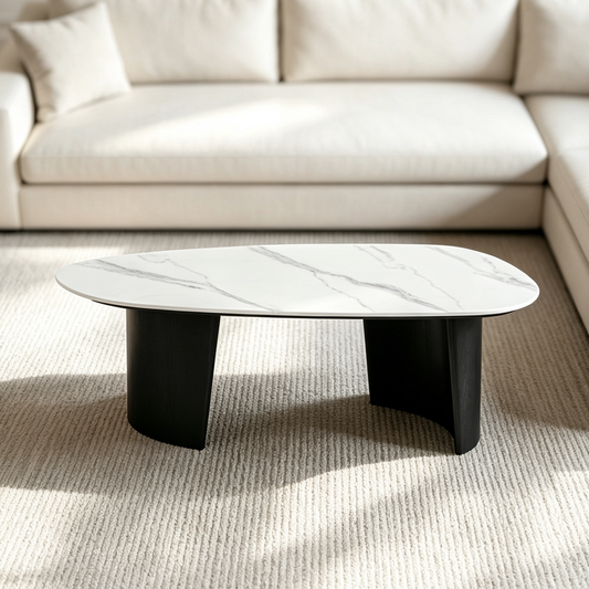 Oval coffee table with a white veined top and curved black supports on a light rug