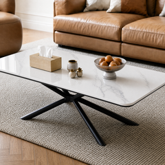 White stone-look coffee table with black crossed legs in a living room