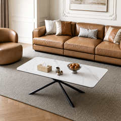 Tan leather-like sectional sofa with assorted light and brown throw pillows, White rectangular coffee table has a black splayed base