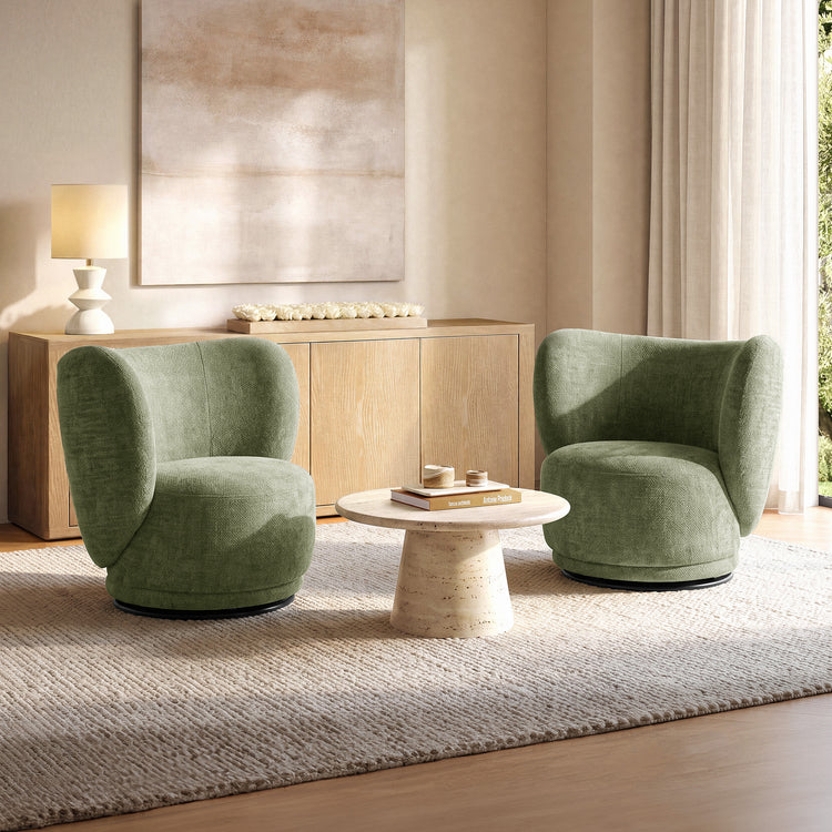 Two green upholstered chairs face a round pedestal coffee table in a bright living room