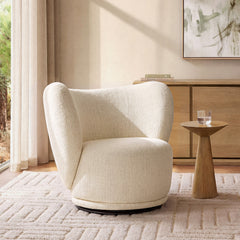 Cream wraparound chair stands beside a tapered pedestal table holding a clear drinking glass