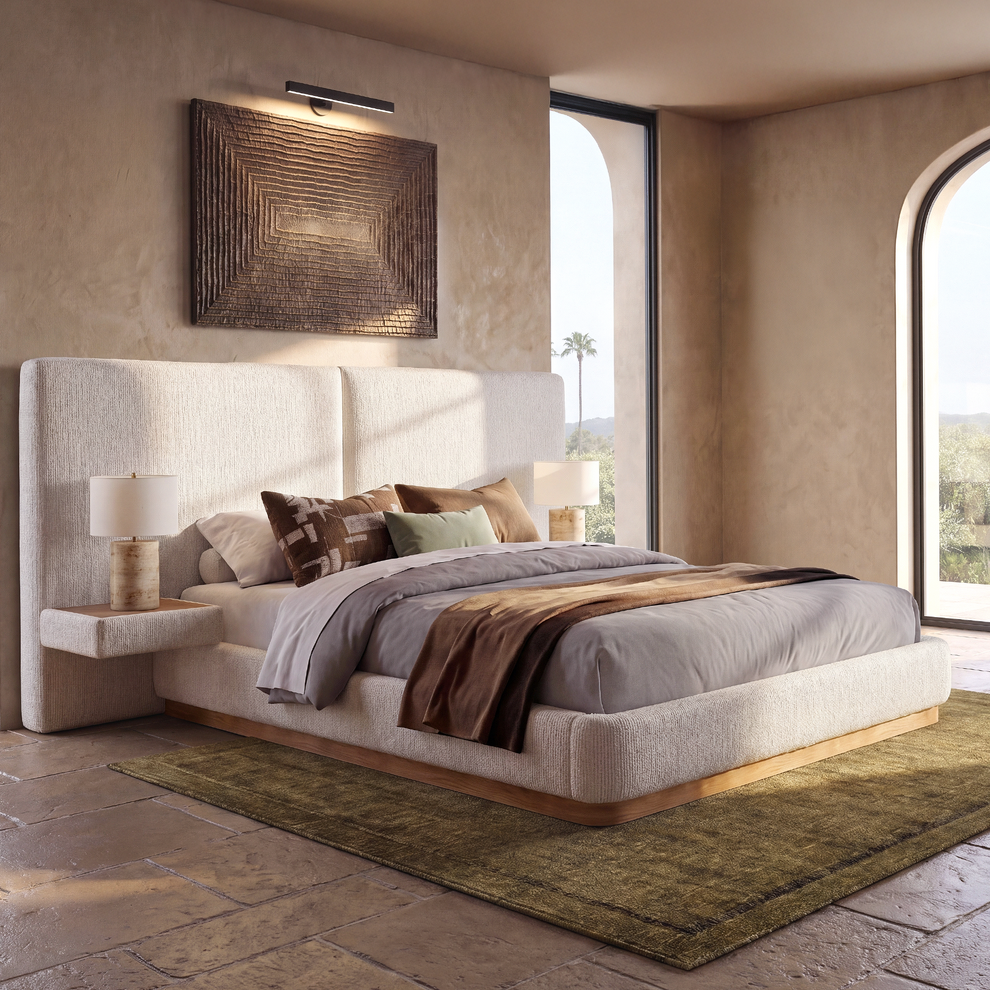 Bed has a broad padded frame and a tall divided headboard, Two lamps flank the pillows
