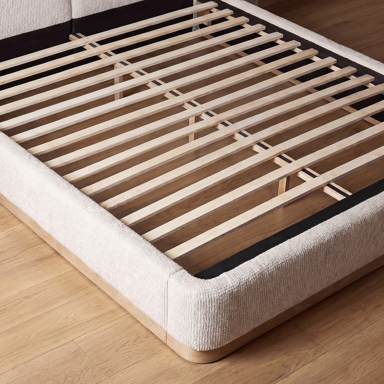 Open upholstered bed frame reveals closely spaced wooden slats and central support rails