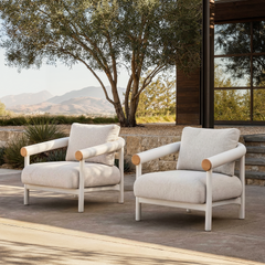 Two matching cream cushioned armchairs are arranged side by side on an outdoor stone patio