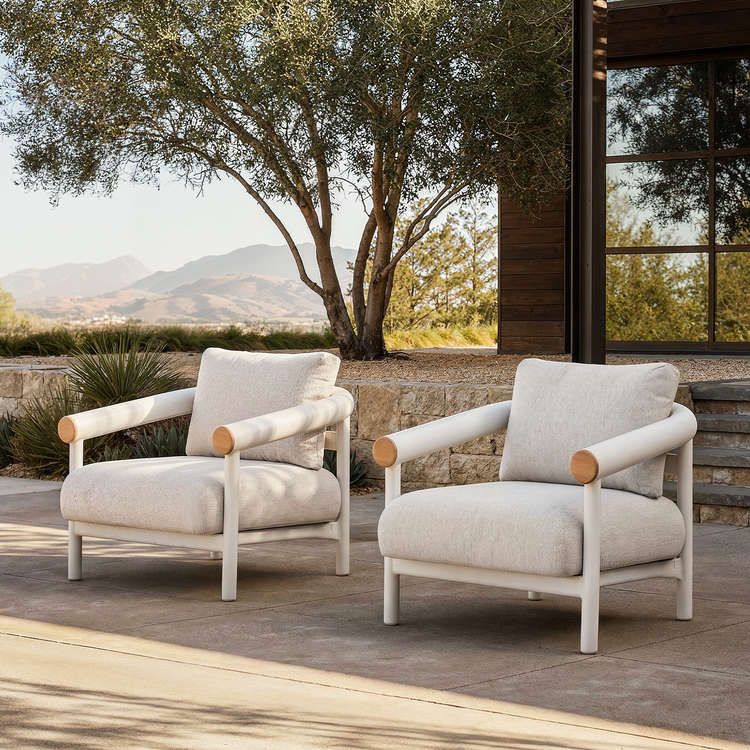 Two matching cream cushioned armchairs are arranged side by side on an outdoor stone patio