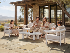 Four people sit on white cushioned patio seating around a low table