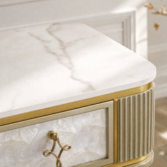Close-up of a white marble-pattern cabinet top, gold trim, fluted corner, and decorative drawer pull