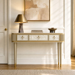 Gold-toned console table has three pale textured drawers and four slim fluted legs