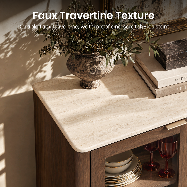 Cream, finely streaked countertop with rounded corners on a brown cabinet, topped with a leafy vase, stacked books and a dark veined box, with dishes and red stemmed glasses visible below.