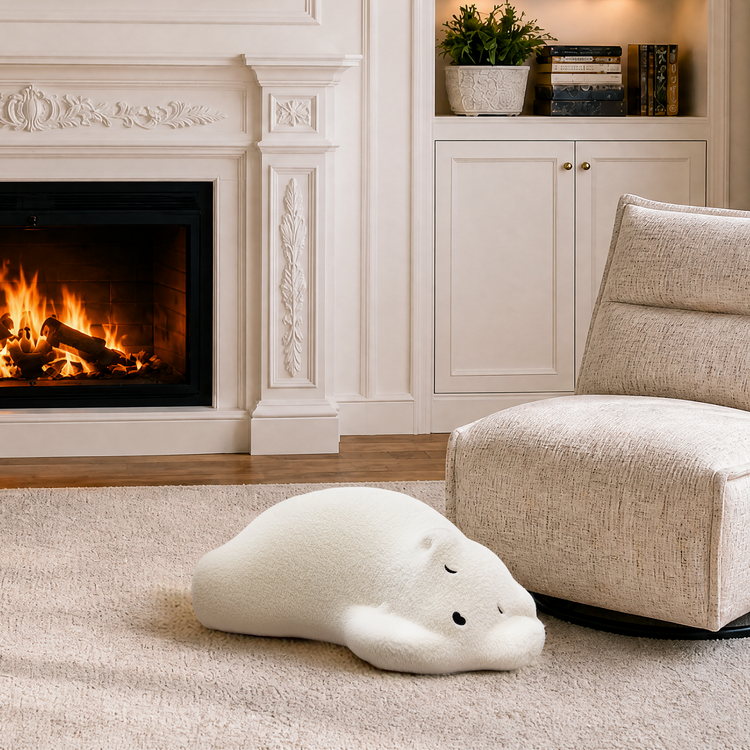 Cream lounge chair and white floor cushion beside a fireplace