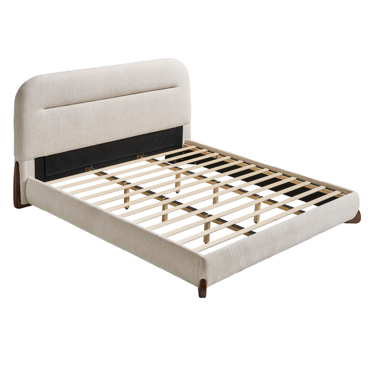 Cream upholstered bed frame with a tall, rounded headboard, a horizontal recessed seam, exposed pale slats, and short dark brown legs, shown without a mattress.