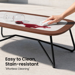 A hand wipes spilled red liquid from the light inset tabletop