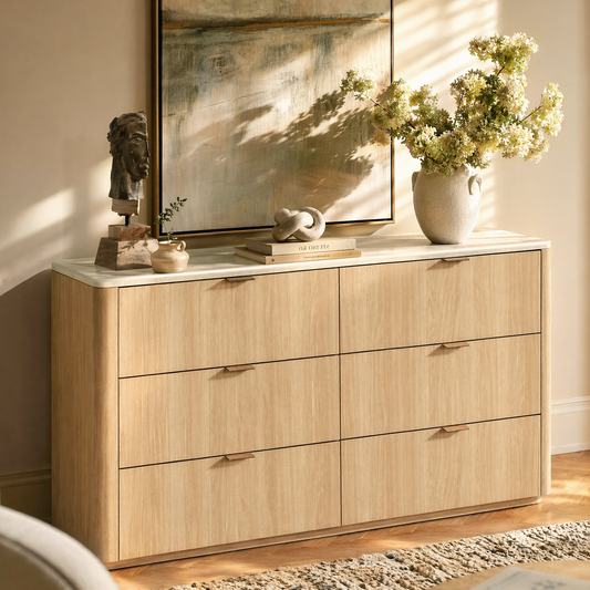 Light wood six-drawer dresser is styled with flowers, books, and sculpture