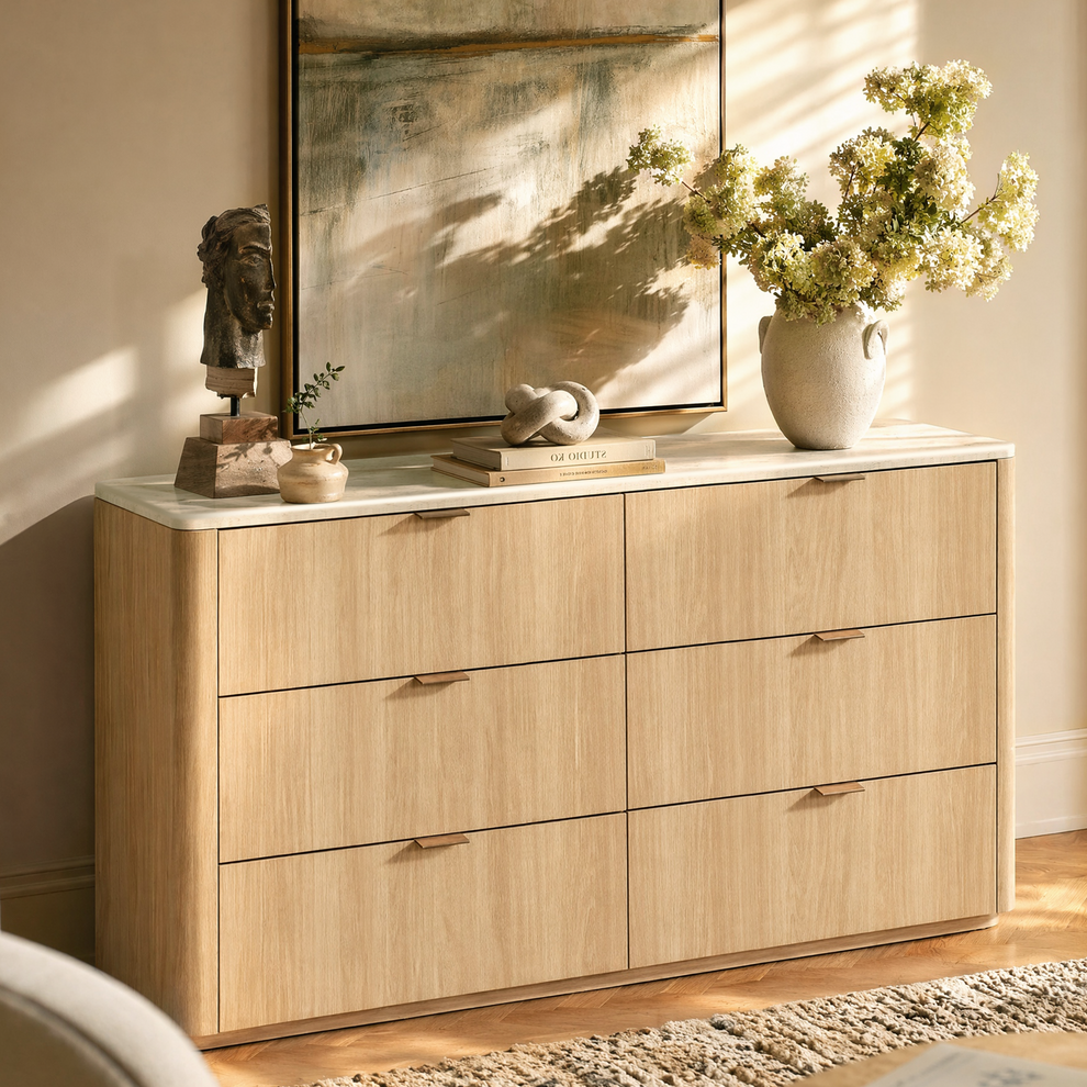 Light wood six-drawer dresser is styled with flowers, books, and sculpture