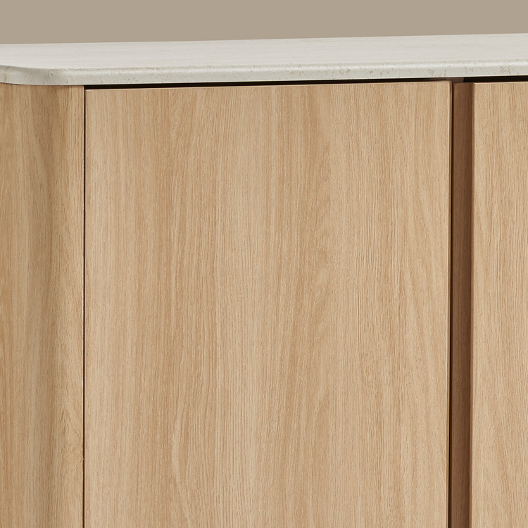 Close-up shows pale wood-grain cabinet fronts beneath a rounded, lightly veined white top
