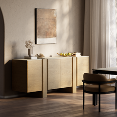 Light wood sideboard styled with books, flowers, and fruit in a sunlit dining room.