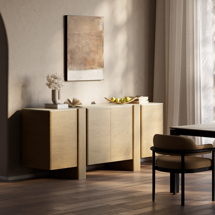 Light wood sideboard styled with books, flowers, and fruit in a sunlit dining room.