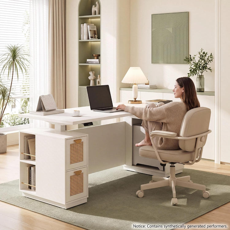 Woman seated in a cream office chair at a white desk with a laptop, lamp, cup and calendar, surrounded by shelves, plants and framed wall art.