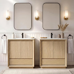 Two light wood-grain vanity cabinets have white sinks and black faucets, Rounded mirrors and three lit wall sconces hang above