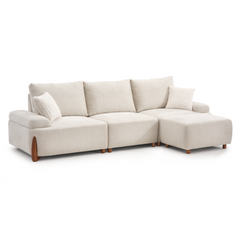 L-shaped cream sectional sofa with three back cushions, two textured throw pillows, rounded arms, and tapered wooden legs.