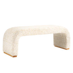 Cream upholstered bench with a textured weave, rounded corners, broad slab legs and short brown feet.