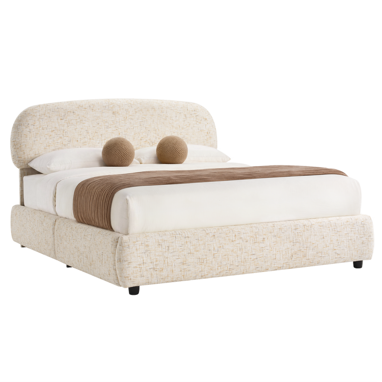 Upholstered bed with a tall rounded headboard, white bedding, two brown spherical cushions, a brown throw, and short dark legs.