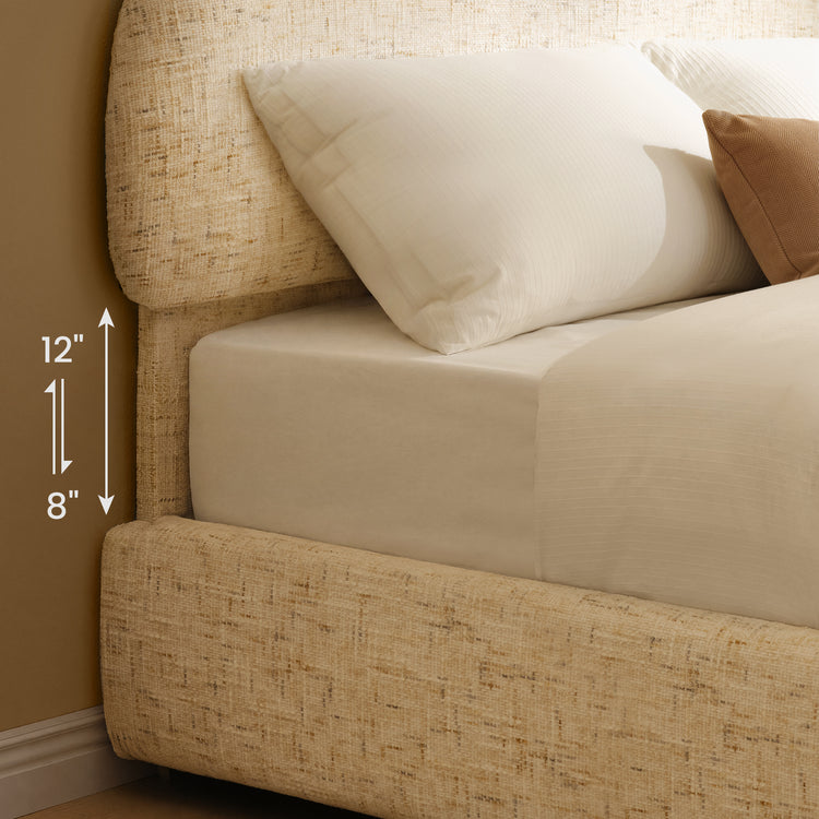 Diagram of a bed with a cream textured frame, white bedding and pillows, and vertical arrows beside the mattress labeled 8 and 12 inches.