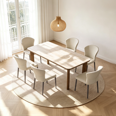 Rectangular dining table with a pale stone-look top, rounded corners and wood-tone legs surrounded by six cream chairs