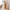 White open bookshelf with wood-tone interior, lighting, books, and decorative objects.