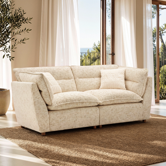 Sandstone beige loveseat sofa with cushions in a bright room beside tall windows