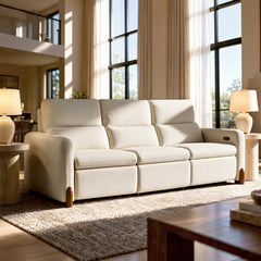 Cream three-seat sofa with cushioned backrests in a sunlit living room.
