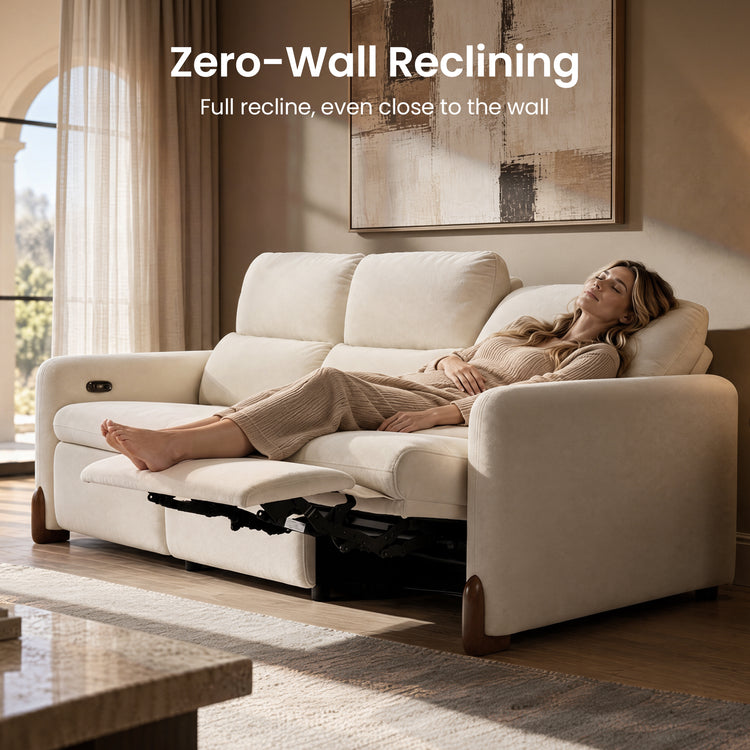 Woman reclining on a cream sofa with an extended footrest.