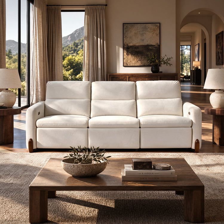 White three-seat sofa with cushioned backrests in a sunlit living room.