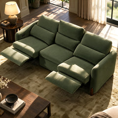 Green three-seat sofa with two footrests extended in a sunlit living room.