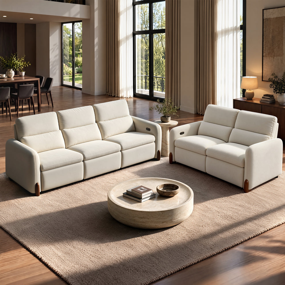 White three-seat sofa and loveseat with padded backs and built-in armrest controls in a sunlit living room.