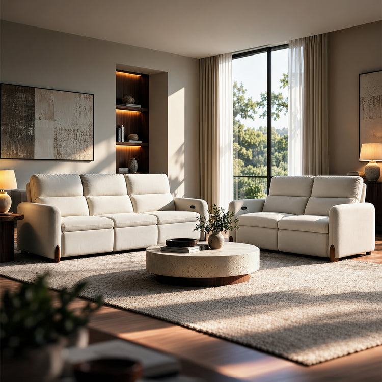 Cream sofa and loveseat arranged around a round coffee table in a sunlit living room.